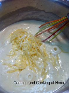 noodles being cooked in a pot with an electric whisk