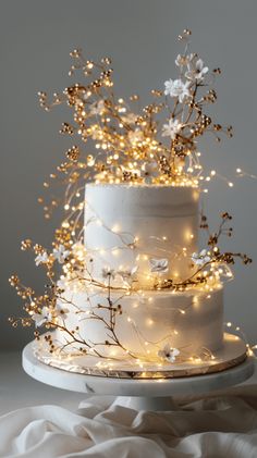 a three tiered cake with white frosting and lights