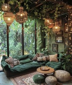 a living room filled with lots of green furniture and hanging lights on the wall above it