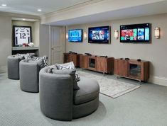 a living room filled with furniture and two flat screen tvs mounted on the wall