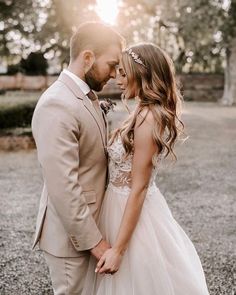 a bride and groom standing close together in front of the sun