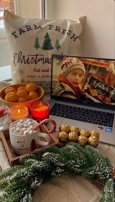 a laptop computer sitting on top of a table next to a tray filled with oranges