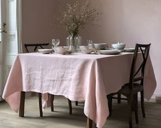 the table is set with dishes and glasses for two people to eat at, along with flowers in vases