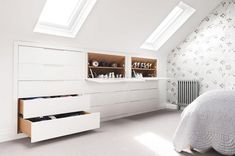 an attic bedroom with white furniture and wallpaper