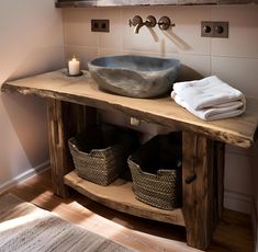 a bathroom sink sitting under a mirror next to a wooden shelf with baskets on it