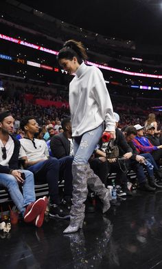 a woman is walking down the runway at a basketball game wearing boots and leggings