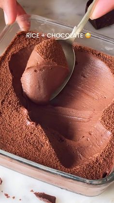 someone is spreading chocolate on top of the cake in a glass dish with a spoon