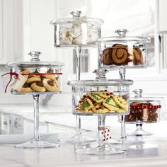 a kitchen counter topped with lots of glass containers filled with cookies and pastries on top of each other