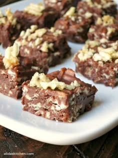 several pieces of brownie on a white plate with chocolate and nuts in the middle