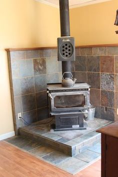 an old fashioned stove is in the corner of a room with tile walls and wood flooring