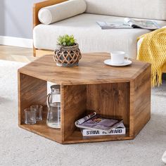 a wooden coffee table with magazines and a cup on it in front of a couch