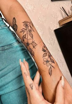 a woman with a tattoo on her arm holding onto another person's arm and the other hand