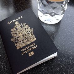 a canadian passport sitting on top of a table next to a glass of water and a cup of coffee