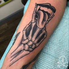 a black and white tattoo on the arm of a person with a skeleton hand holding a knife