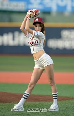 a female baseball player in action on the field with her glove raised up to catch the ball