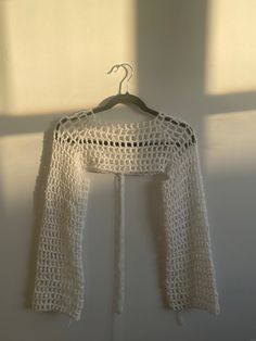 a white crocheted jacket hanging on a wall