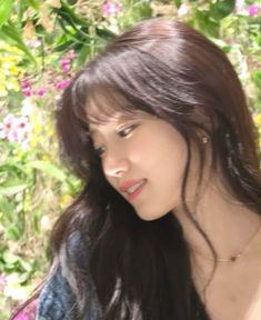 a woman with long hair standing in front of flowers