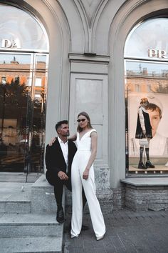 a man standing next to a woman in front of a store window with mannequins on the windows