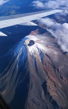 an airplane wing flying over a mountain covered in clouds