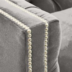 the back of a gray couch with pearls on it's arms and footrests