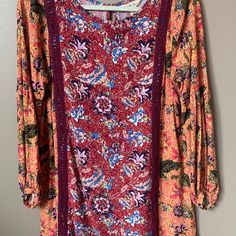 a dress hanging on a hanger in front of a white wall with a red and blue floral pattern