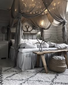 a canopy bed with lights hanging from it's sides and pillows on the floor