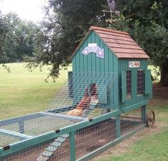 a green chicken coop with two chickens in it's cage and a dog inside