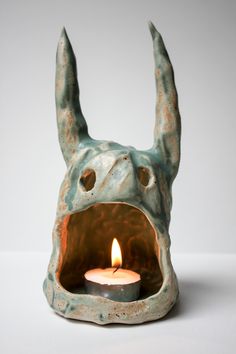 a candle that is inside of a ceramic animal head with it's mouth open