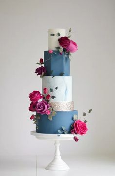 a multi - tiered cake with flowers on the top and bottom is decorated with blue icing