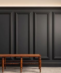 a wooden bench in front of black paneled walls