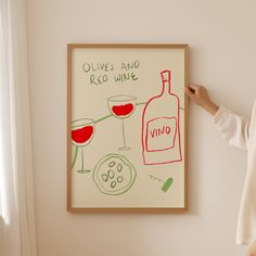 a woman standing next to a painting with wine glasses on it