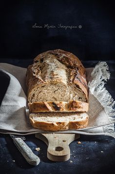 a loaf of bread sitting on top of a wooden cutting board next to a knife