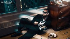 a man in a suit and sunglasses sitting on a bench eating food from a plate