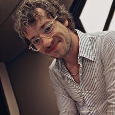 a man with curly hair and glasses posing for the camera