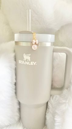 the tumbler cup has a gold chain attached to it's handle and is sitting on a fluffy white blanket