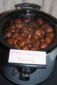 a close up of food in a pot with a sign on the lid that says roasted zombie eyeballs