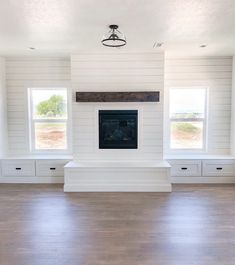 an empty living room with white painted walls and wood flooring on the far wall