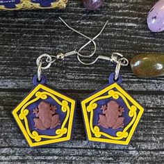 the earrings are decorated with an image of a woman's head on purple and yellow