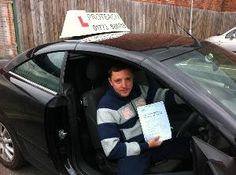 a man sitting in the driver's seat of a car holding a piece of paper