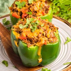 two stuffed peppers on a white plate with a wooden spoon