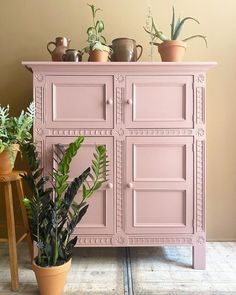 a pink cabinet with potted plants on top