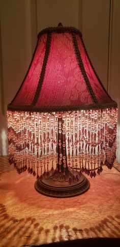 a lamp that is sitting on top of a table with a red shade over it