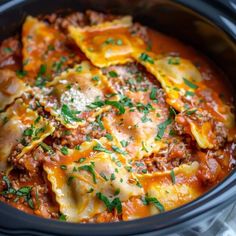 a crock pot filled with lasagna sauce and cheese, topped with parsley