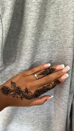 a woman's hand with henna tattoos on it