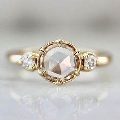 an engagement ring with a white diamond surrounded by three smaller diamonds on the band, in yellow gold