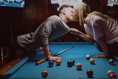 a man and woman kissing while playing pool