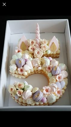 a cake in a box with flowers and unicorn ears on it