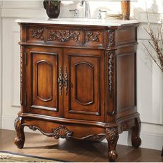 an antique style bathroom vanity with marble top and carved wood accents, in a white walled room