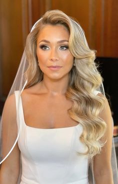 a woman with long blonde hair wearing a white wedding dress and veil over her head