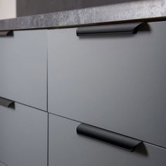 a close up of a gray cabinet with black handles and knobs on the drawers